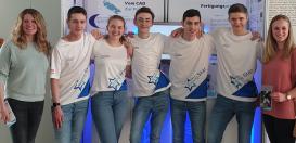 Die Mitglieder des Teams Rising Star mit Frau Spaller und Frau Mohner vor ihrem Boxenstand auf der NRW-Meisterschaft des Wettbewerbs Formel Eins in der Schule.
