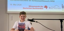 Koray las beim Landesentscheid des Vorlesewettberbs NRW aus dem Buch „Als die Welt uns gehörte. Drei Freunde, zwei Seiten, eine Erinnerung“ von Liz Kessler.