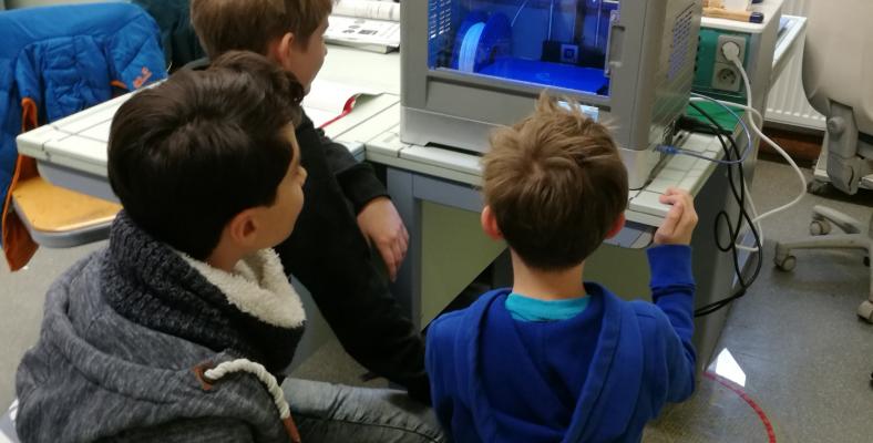 Die Schülerinnen und Schüler der Klasse 7b beobachten interessiert das Geschehen im 3D-Drucker.