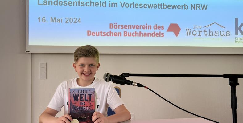Koray las beim Landesentscheid des Vorlesewettberbs NRW aus dem Buch „Als die Welt uns gehörte. Drei Freunde, zwei Seiten, eine Erinnerung“ von Liz Kessler.